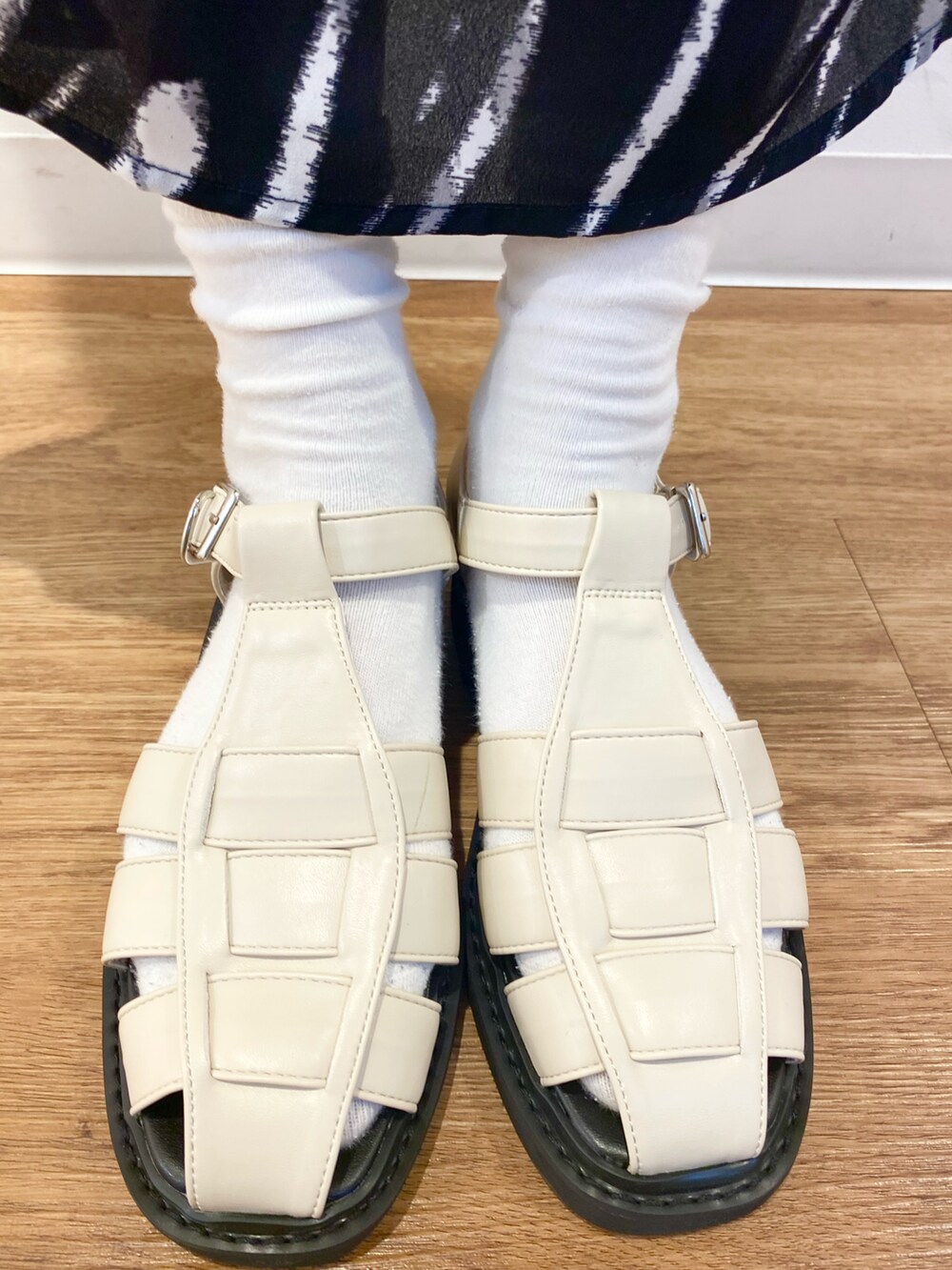 ブラック系のスカート、ベージュ系のその他アウター、ホワイト系のサンダルを着用したレディースの春コーディネートの5枚目の写真