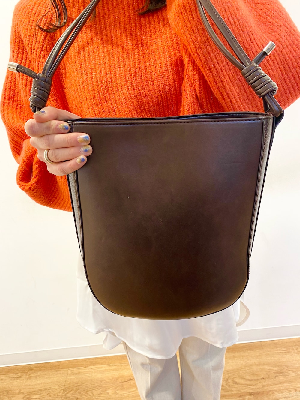 レッド系のニット/セーター、ホワイト系のシャツ/ブラウス、ブラウン系のショルダーバッグを着用したレディースの冬コーディネートの4枚目の写真
