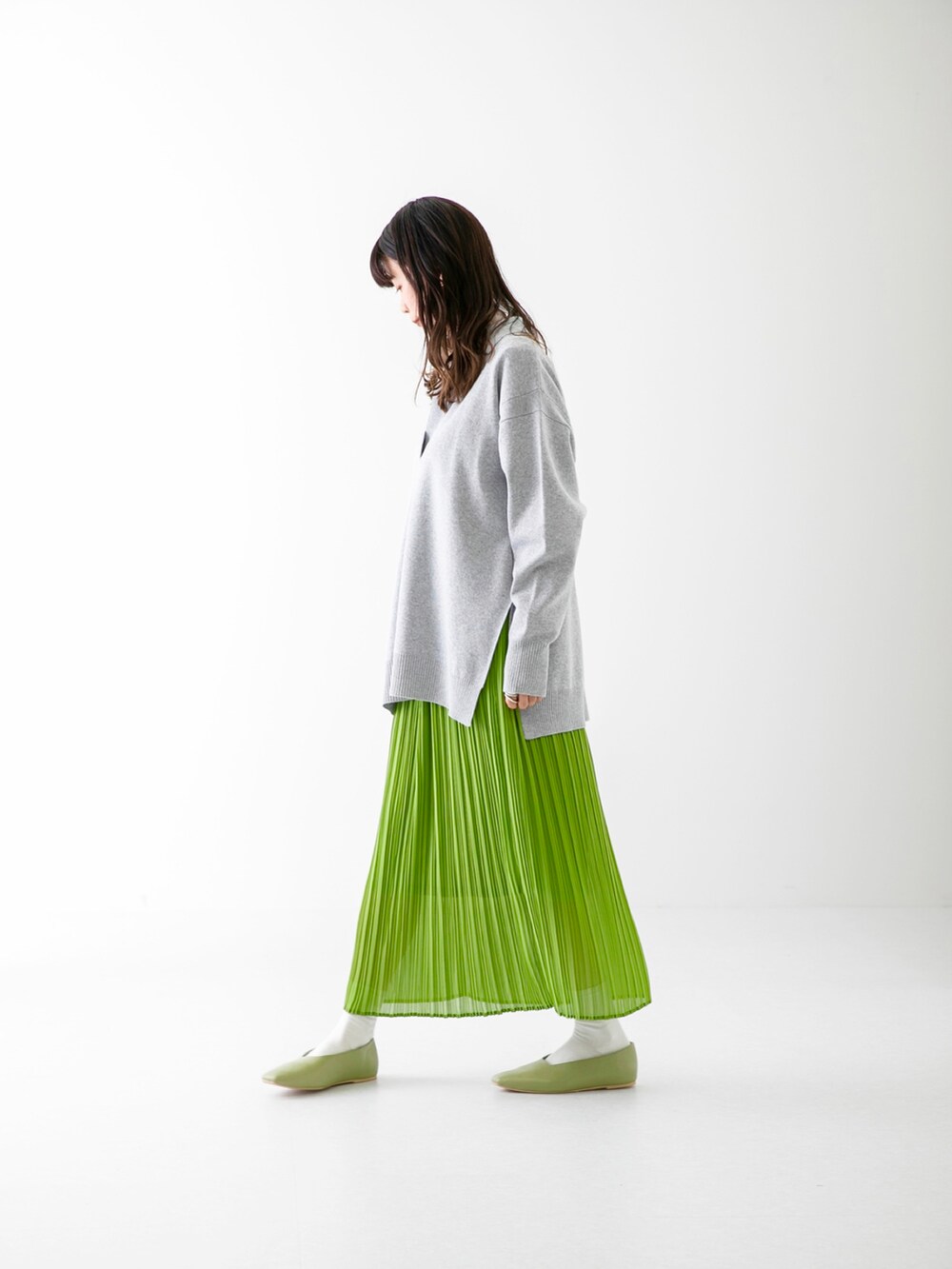 グリーン系のスカート、グレー系のニット/セーター、ホワイト系のその他トップスを着用したレディースの春コーディネートの3枚目の写真