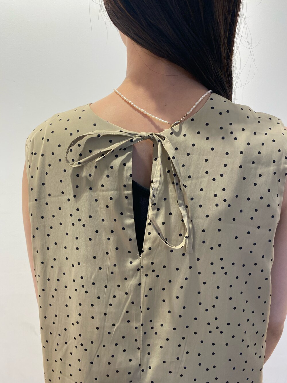 ベージュ系のワンピース、ブルー系のデニムパンツ、グリーン系のハンドバッグを着用したレディースの夏コーディネートの4枚目の写真