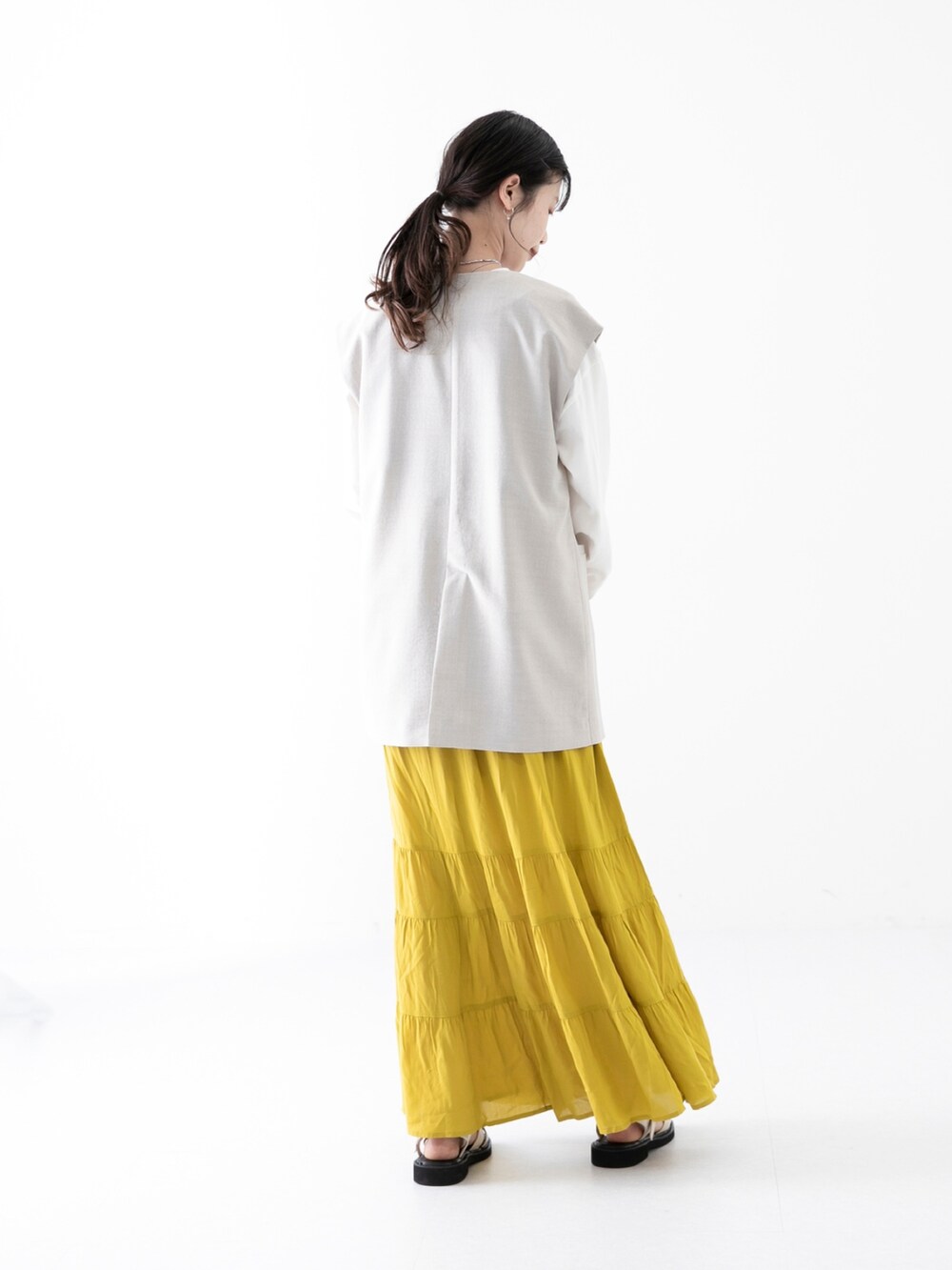 ベージュ系のその他アウター、イエロー系のスカート、その他のTシャツ/カットソーを着用したレディースの春コーディネートの2枚目の写真