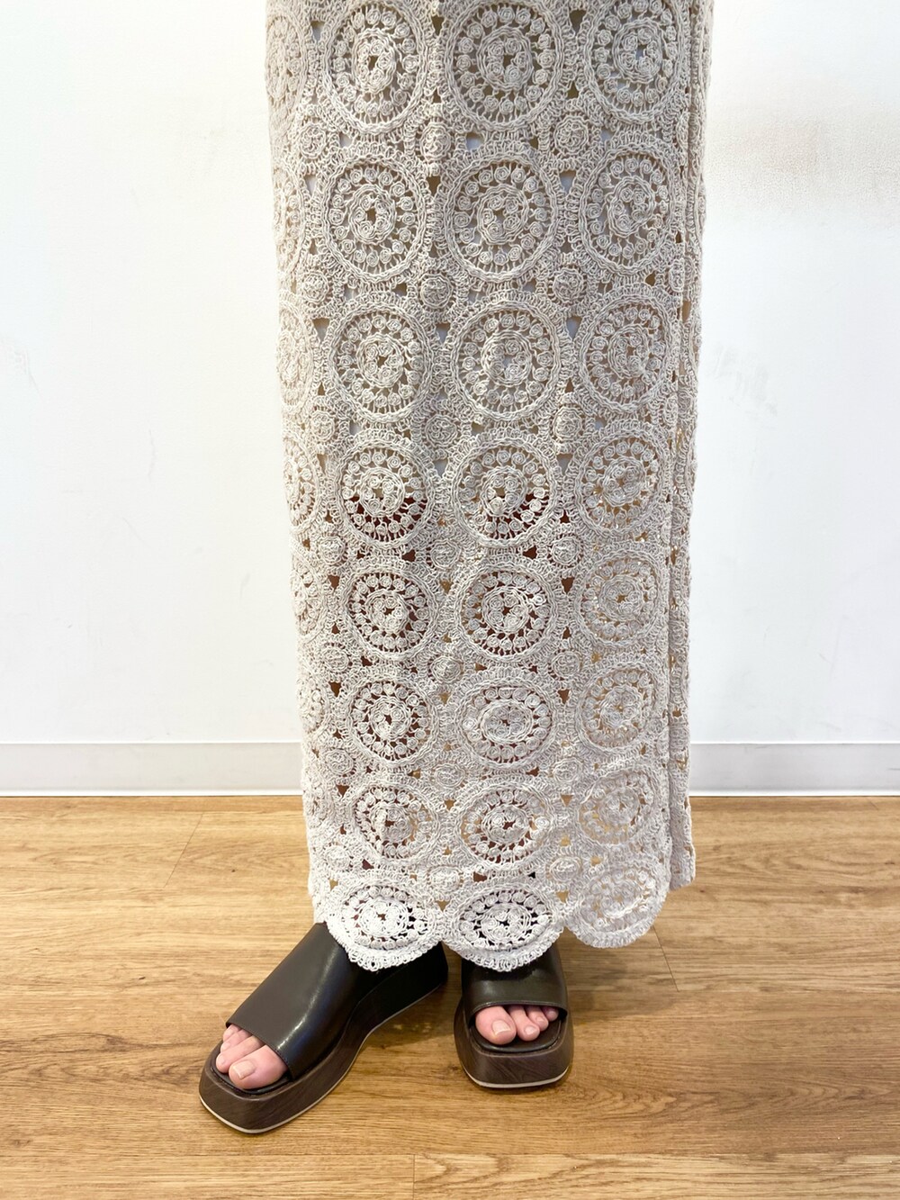 ホワイト系のスカート、ブラウン系のサンダル、ベージュ系のその他アウターを着用したレディースの春コーディネートの5枚目の写真