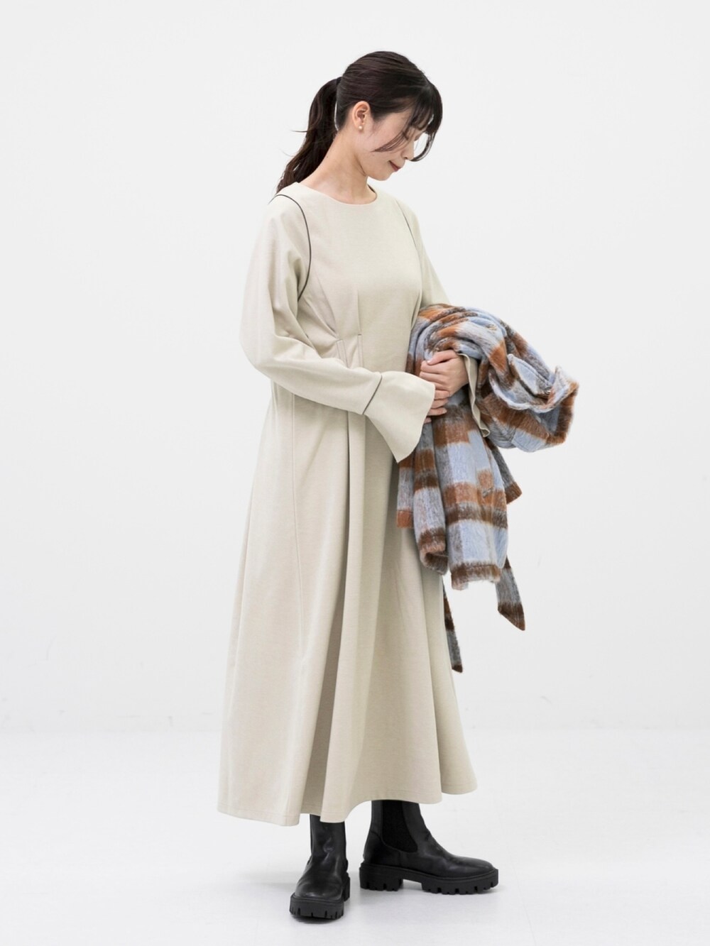 ブラック系のブーツ、ブルー系のステンカラーコート、ホワイト系のワンピースを着用したレディースの秋コーディネートの2枚目の写真