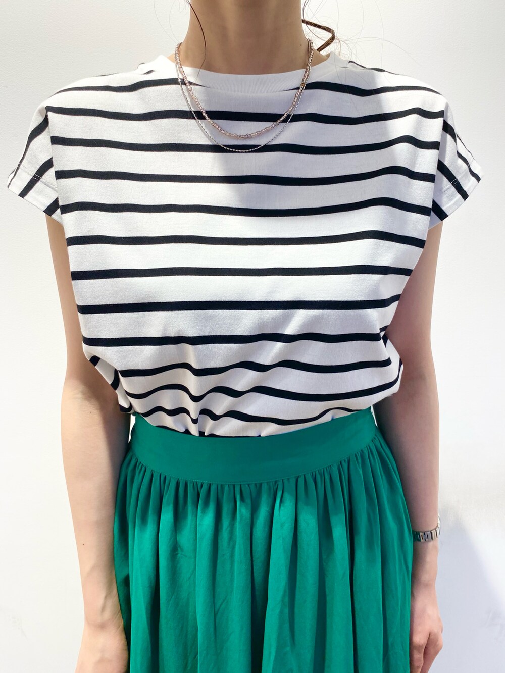 ホワイト系のTシャツ/カットソー、グリーン系のスカート、グリーン系のサンダルを着用したレディースの春コーディネートの4枚目の写真