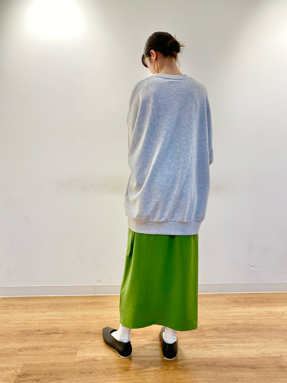 グレー系のスウェット、グリーン系のスカート、ホワイト系のショルダーバッグを着用したレディースの冬コーディネートの2枚目の写真