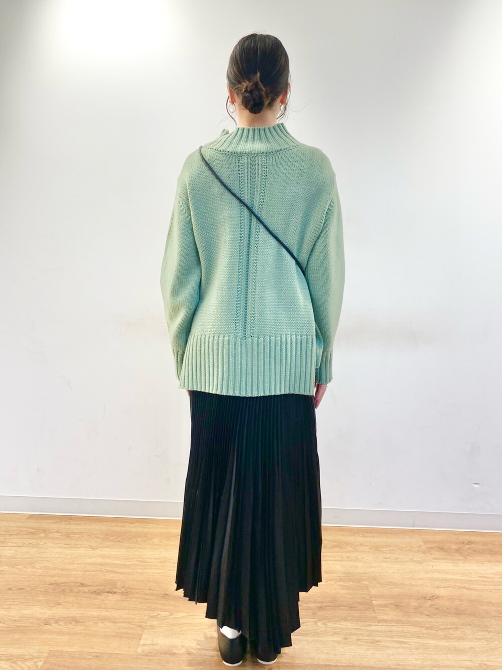 グリーン系のニット/セーター、ベージュ系のショルダーバッグ、ブラック系のスカートを着用したレディースの冬コーディネートの3枚目の写真