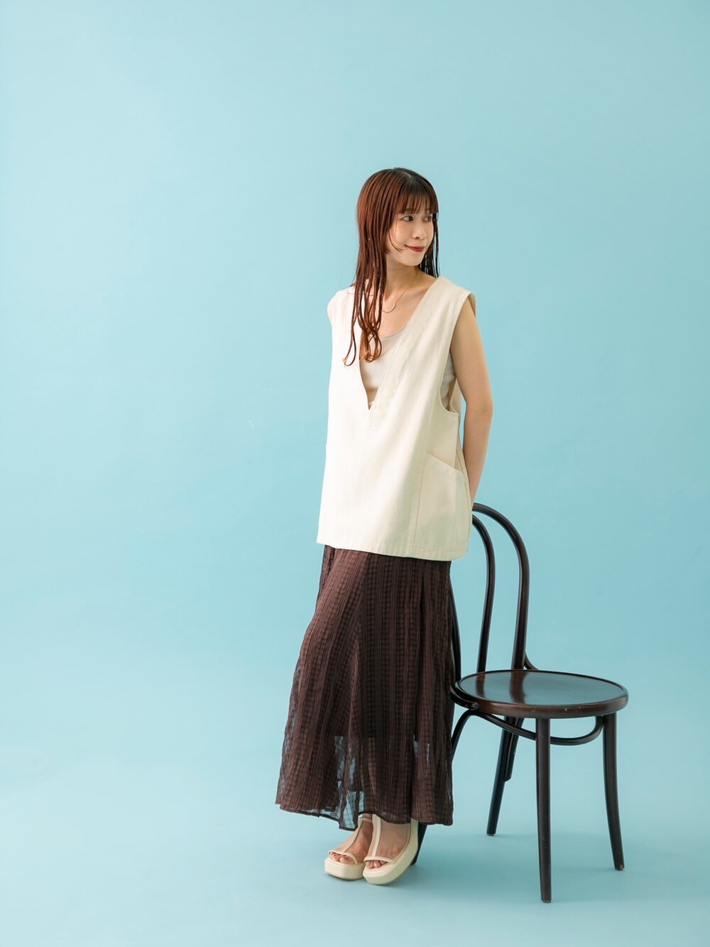 ホワイト系のベスト、ベージュ系のキャミソール、ホワイト系のサンダルを着用したレディースの春コーディネートの2枚目の写真