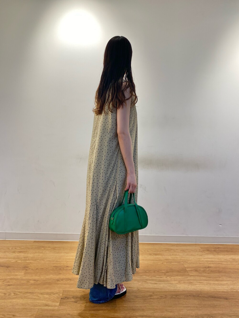 ベージュ系のワンピース、ブルー系のデニムパンツ、グリーン系のハンドバッグを着用したレディースの夏コーディネートの2枚目の写真