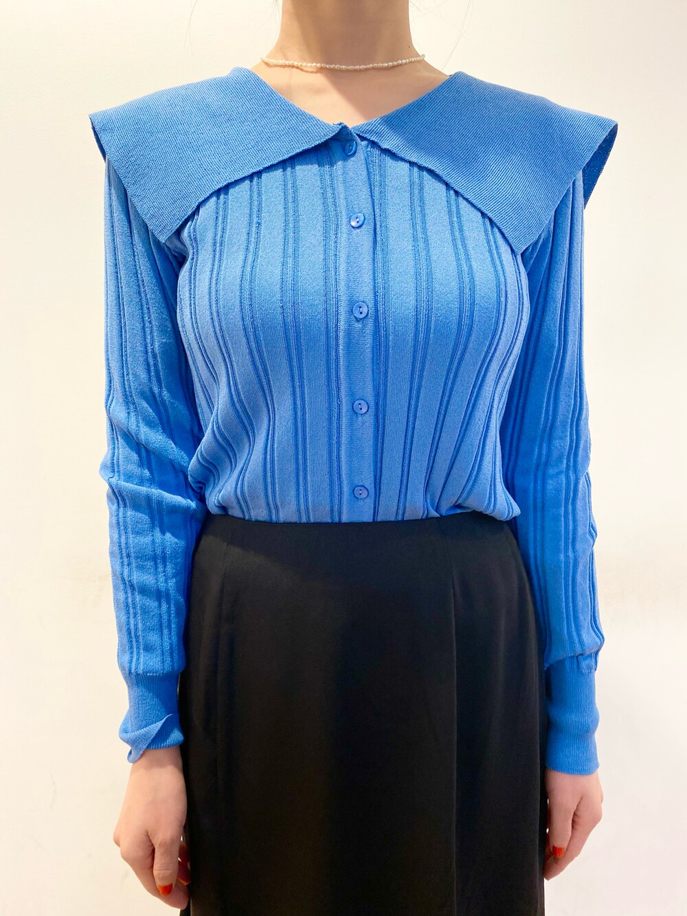 ブルー系のカーディガン/ボレロ、ブラック系のスカート、ブラック系のショルダーバッグを着用したレディースの春コーディネートの4枚目の写真