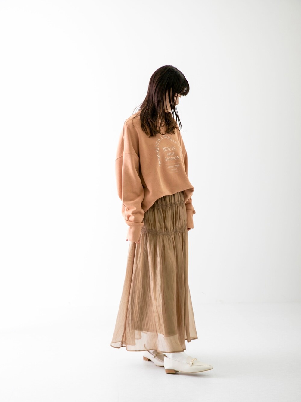 ピンク系のスウェット、ベージュ系のスカート、ホワイト系のローファーを着用したレディースの春コーディネートの2枚目の写真