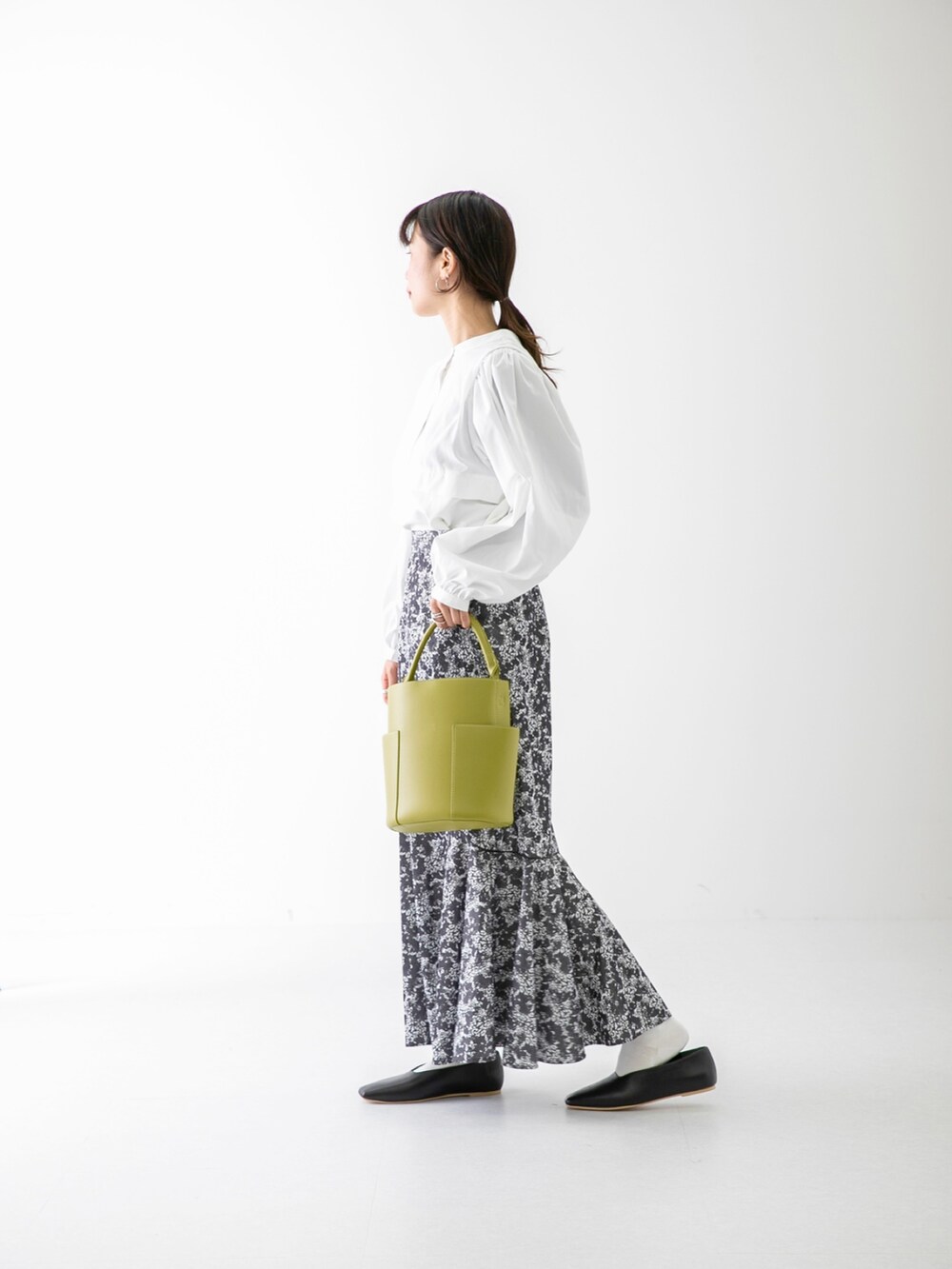 ホワイト系のTシャツ/カットソー、グリーン系のトートバッグ、ブラック系のスカートを着用したレディースの冬コーディネートの2枚目の写真