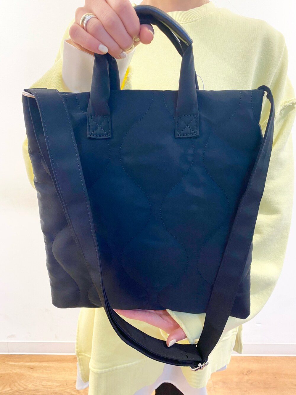 イエロー系のスウェット、ブラック系のトートバッグ、ホワイト系のシャツ/ブラウスを着用したレディースの冬コーディネートの2枚目の写真