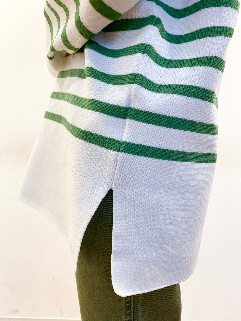 ブラウン系のトートバッグ、グリーン系のニット/セーター、グリーン系のデニムパンツを着用したレディースの冬コーディネートの3枚目の写真