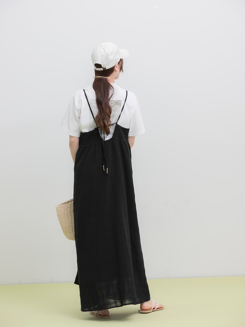 ブラック系のワンピース、ホワイト系のトートバッグ、ホワイト系のサンダルを着用したレディースの夏コーディネートの3枚目の写真