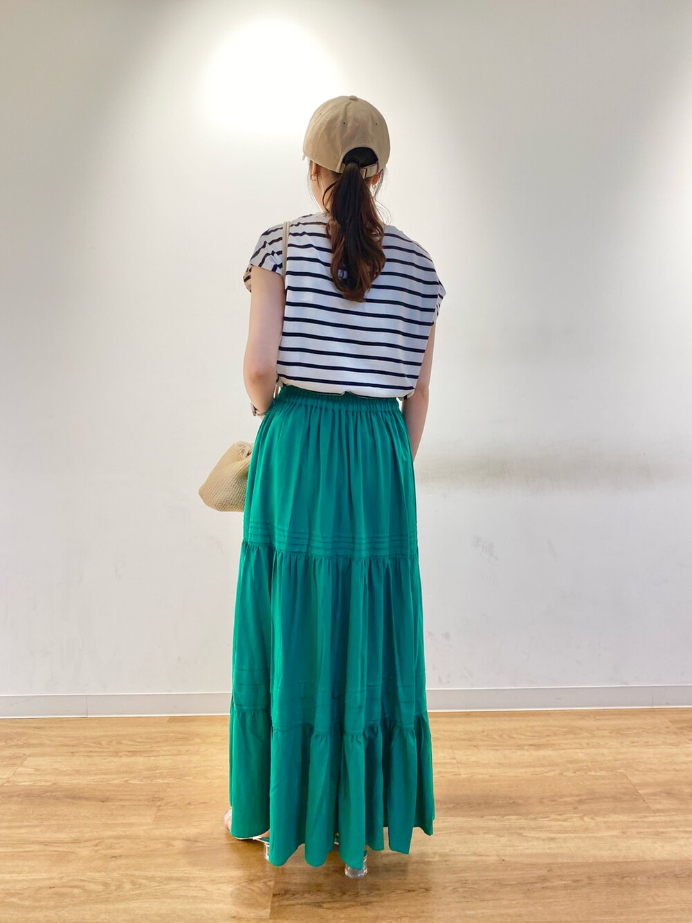 ホワイト系のTシャツ/カットソー、グリーン系のスカート、グリーン系のサンダルを着用したレディースの春コーディネートの3枚目の写真