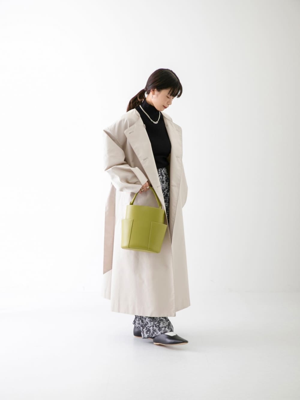 ブラック系のニット/セーター、ベージュ系のトレンチコート、ブラック系のその他パンツを着用したレディースの春コーディネートの4枚目の写真