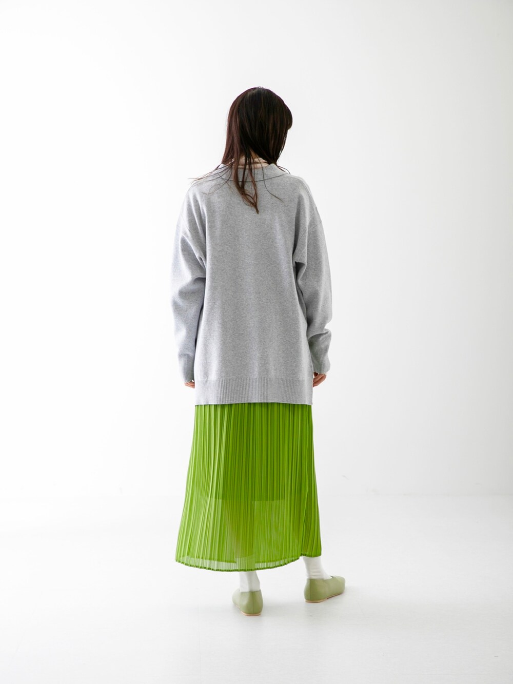 グリーン系のスカート、グレー系のニット/セーター、ホワイト系のその他トップスを着用したレディースの春コーディネートの2枚目の写真