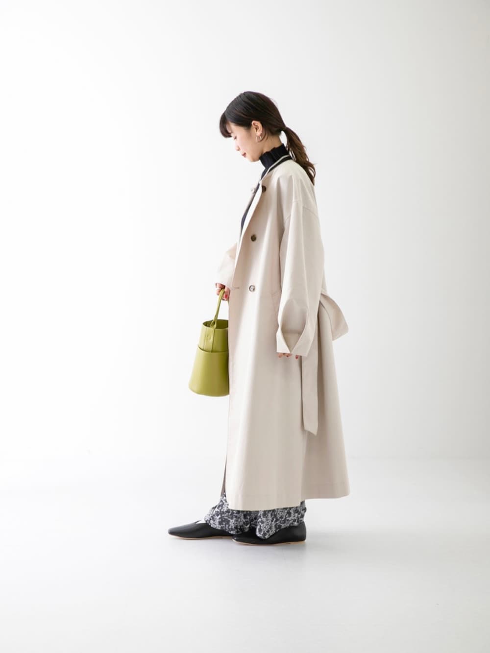 ブラック系のニット/セーター、ベージュ系のトレンチコート、ブラック系のその他パンツを着用したレディースの春コーディネートの5枚目の写真