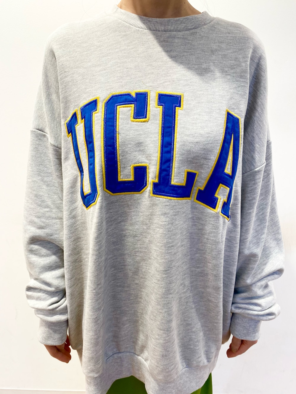 グレー系のスウェット、グリーン系のスカート、ホワイト系のショルダーバッグを着用したレディースの冬コーディネートの4枚目の写真