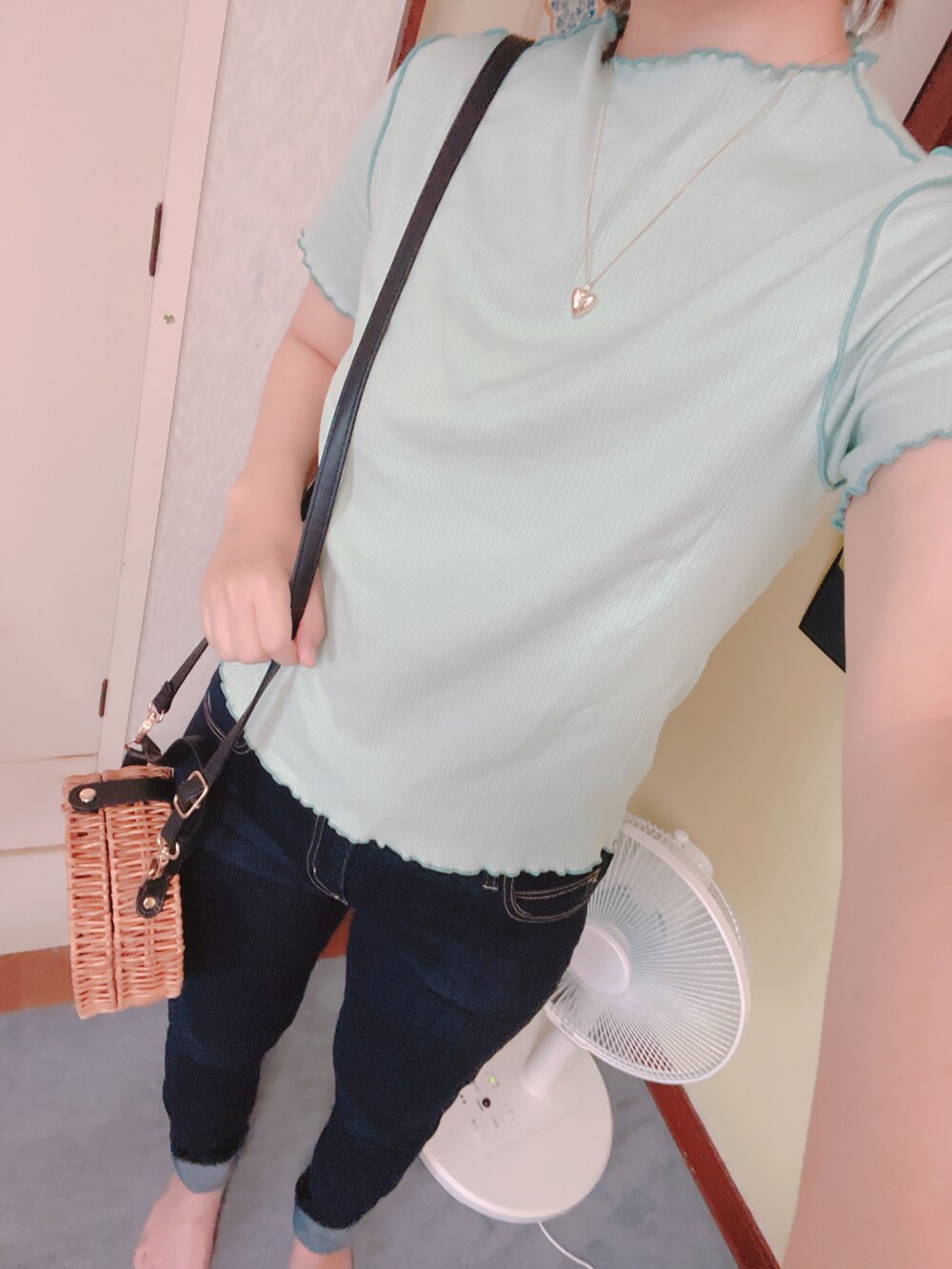 ブルー系のデニムパンツ、グリーン系のTシャツ/カットソー、ブラック系のかごバッグを着用したレディースの夏コーディネートの2枚目の写真