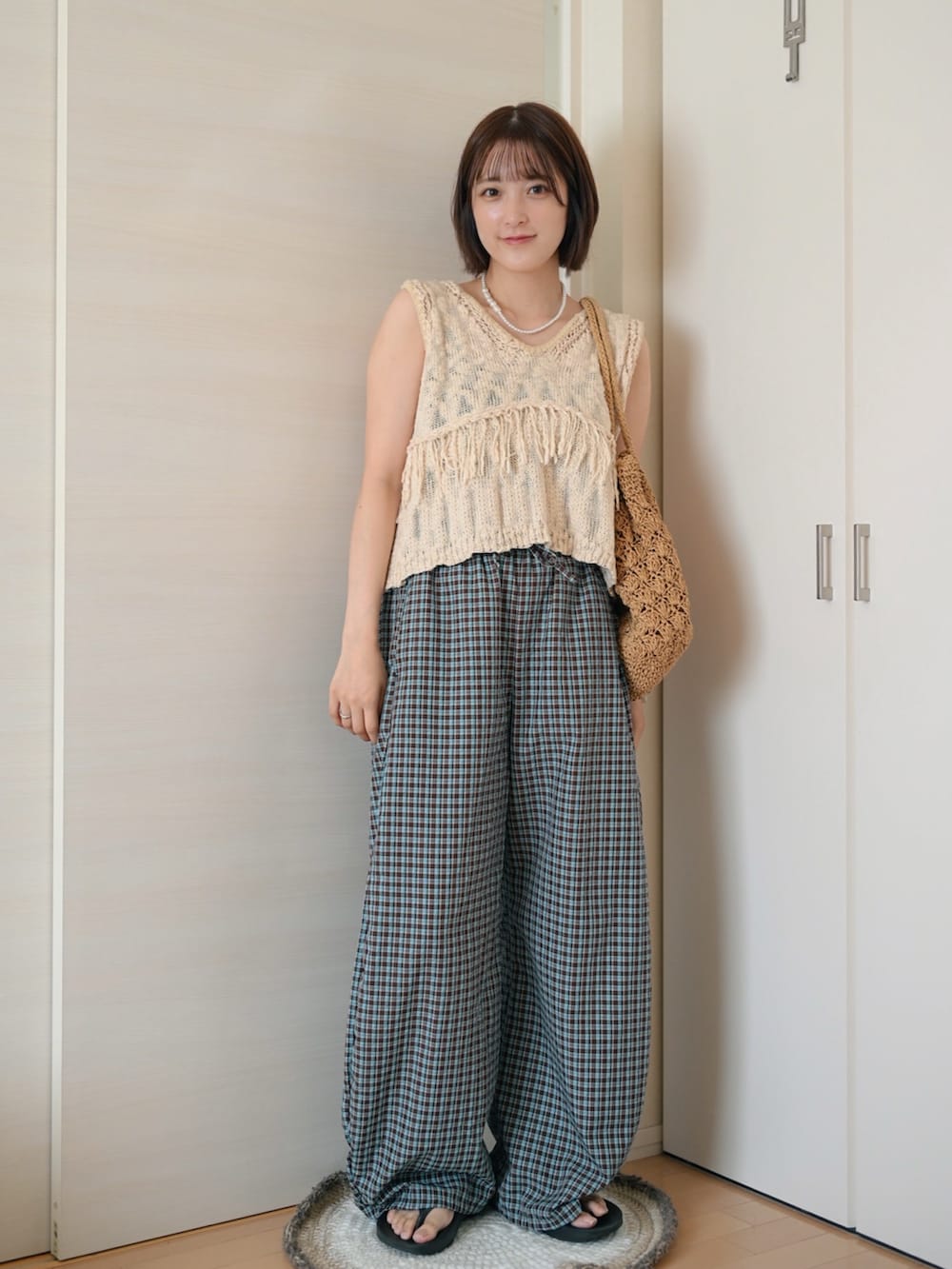 ホワイト系のベスト、ブラウン系のその他パンツ、ブラック系のサンダルを着用したレディースの夏コーディネートの2枚目の写真