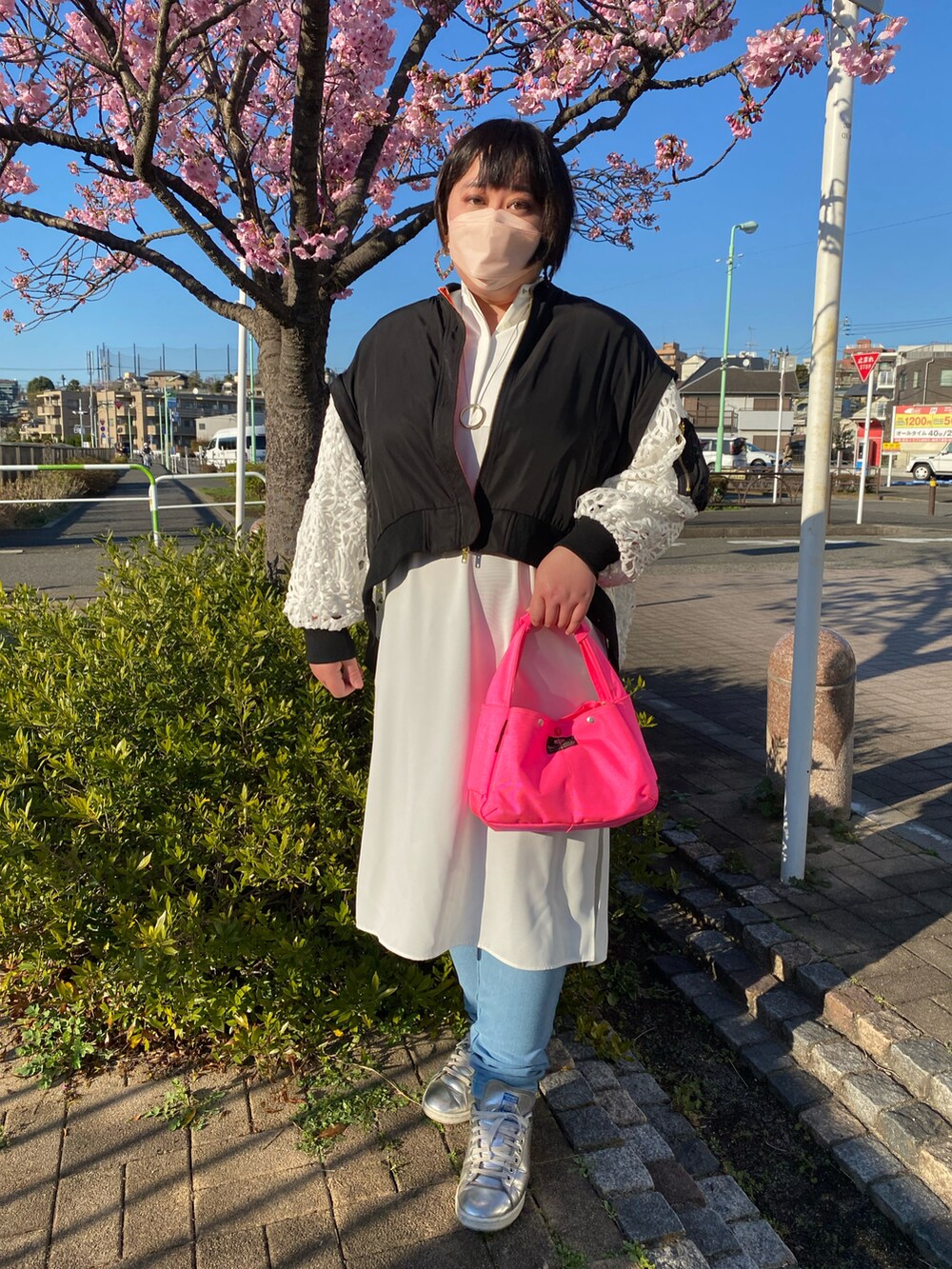 ピンク系のハンドバッグ、ホワイト系のワンピース、ブラック系のブルゾンを着用したレディースの春コーディネートの2枚目の写真