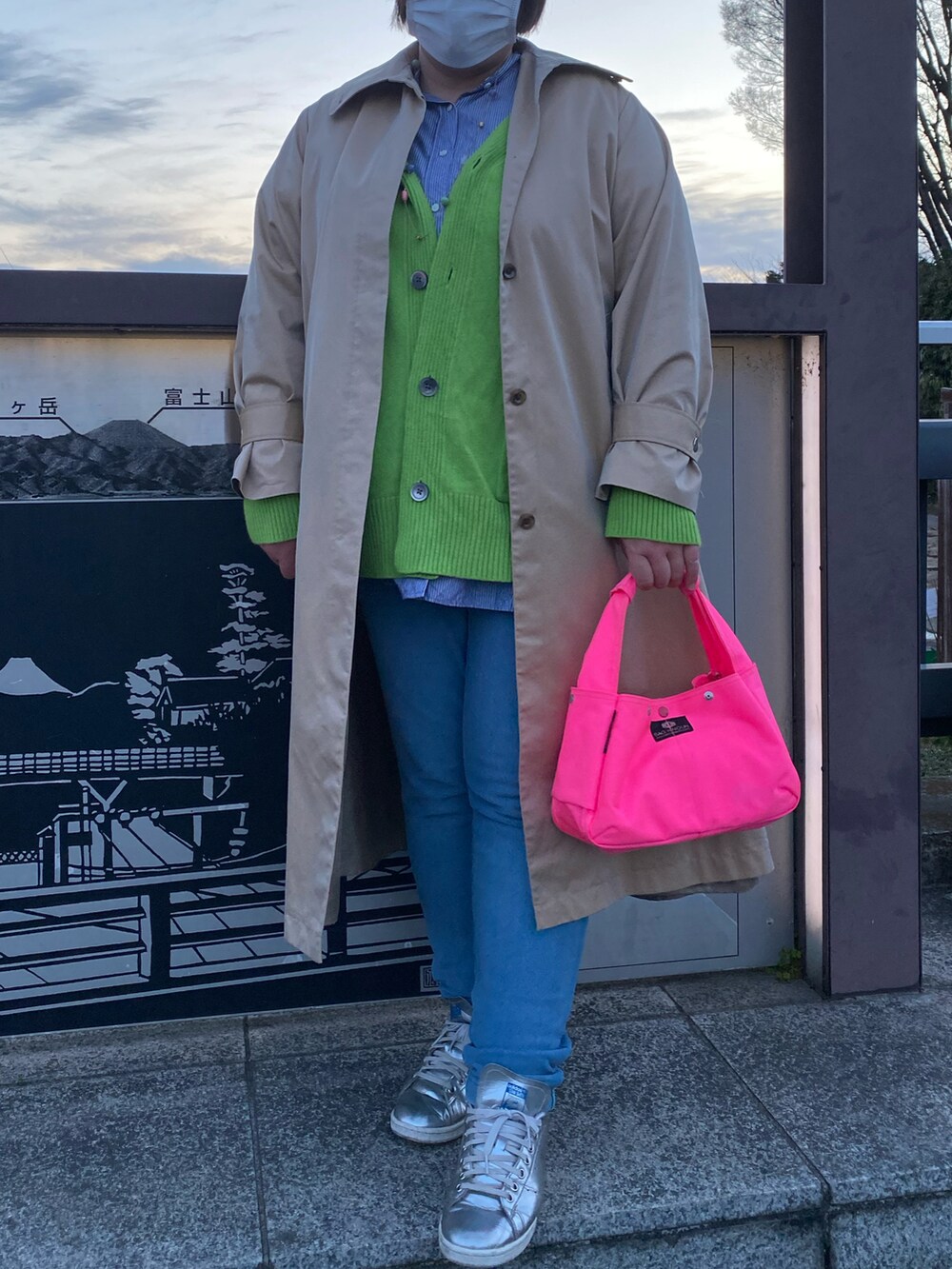 ピンク系のハンドバッグ、ベージュ系のステンカラーコート、グリーン系のカーディガン/ボレロを着用したレディースの春コーディネートの3枚目の写真