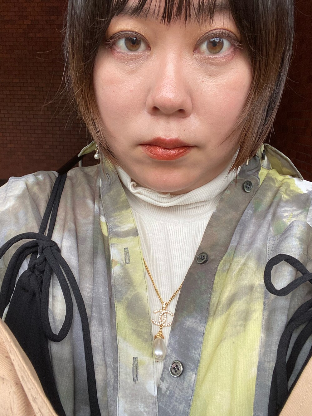 ベージュ系のジャケット/アウター、グリーン系のシャツ/ブラウス、ブラック系のオールインワン・サロペットを着用したレディースの春コーディネートの2枚目の写真