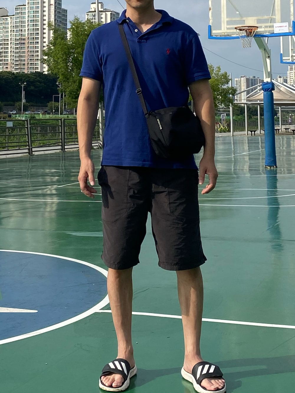 ブルー系のポロシャツ、ブラック系のその他パンツ、ブラック系のバッグを着用したメンズの秋コーディネートの5枚目の写真