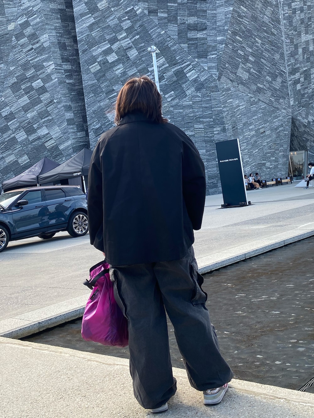 ブラック系のステンカラーコート、グレー系のデニムパンツを着用したレディースの春コーディネートの3枚目の写真