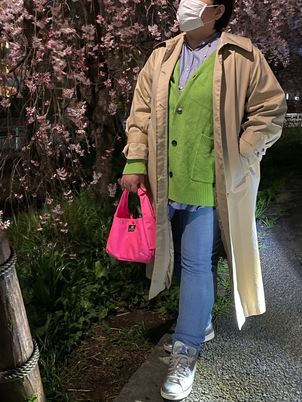 ピンク系のハンドバッグ、ベージュ系のステンカラーコート、グリーン系のカーディガン/ボレロを着用したレディースの春コーディネートの2枚目の写真