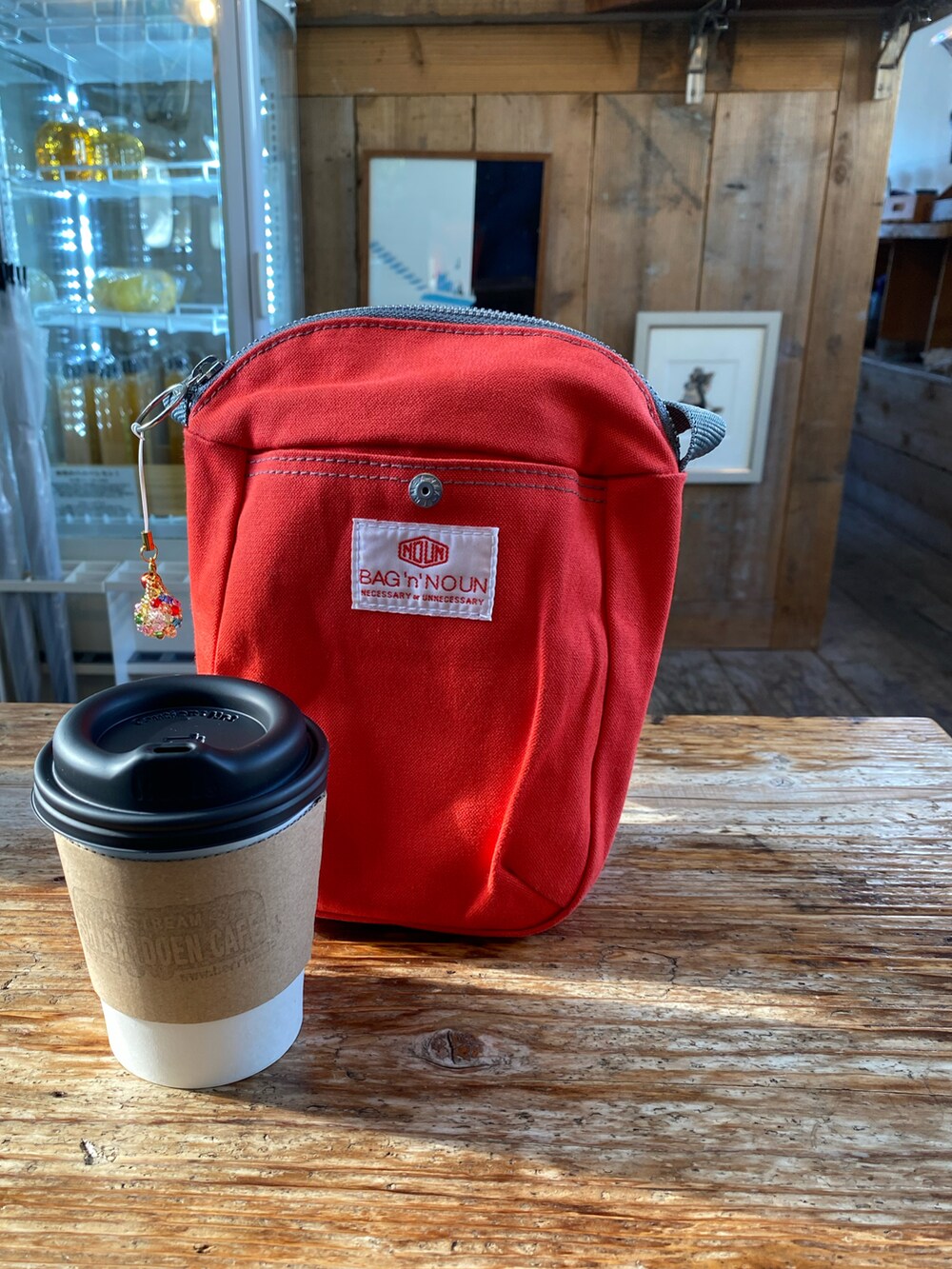 ベージュ系のステンカラーコート、ブラック系のTシャツ/カットソー、レッド系のバッグを着用したレディースの冬コーディネートの4枚目の写真