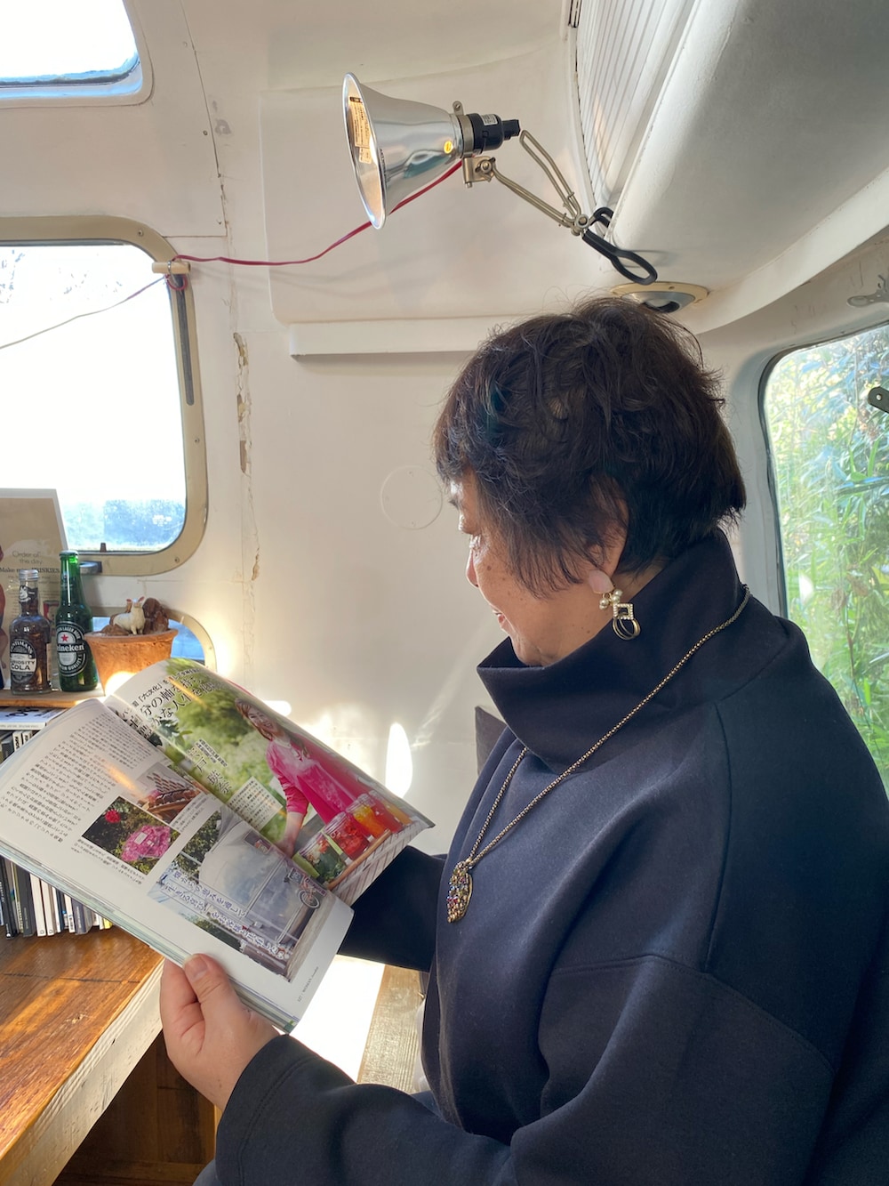 ベージュ系のステンカラーコート、ブラック系のTシャツ/カットソー、レッド系のバッグを着用したレディースの冬コーディネートの3枚目の写真