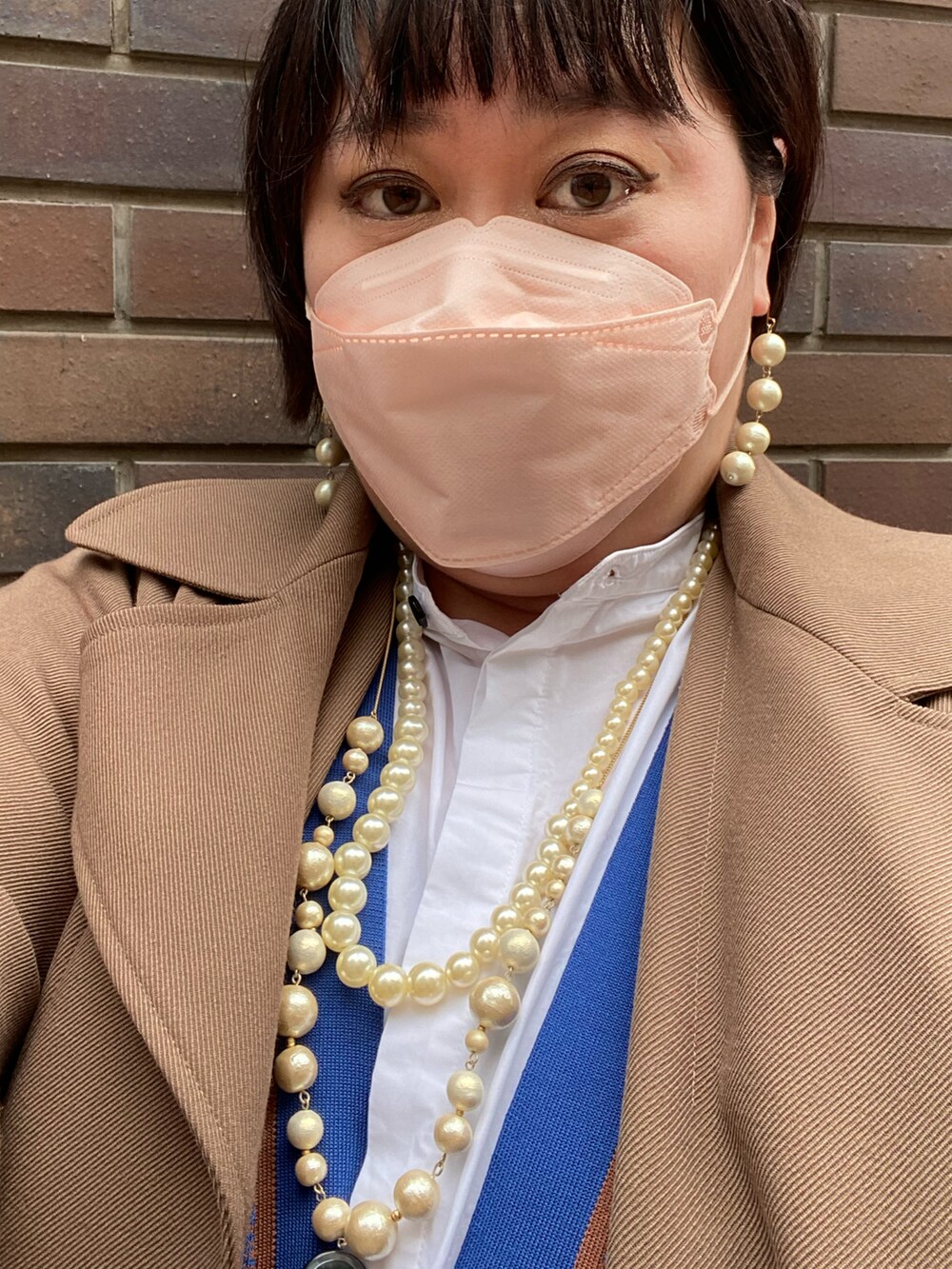 ブラウン系のトレンチコート、ブルー系のカーディガン/ボレロ、ブラック系のスウェットパンツを着用したレディースの春コーディネートの2枚目の写真