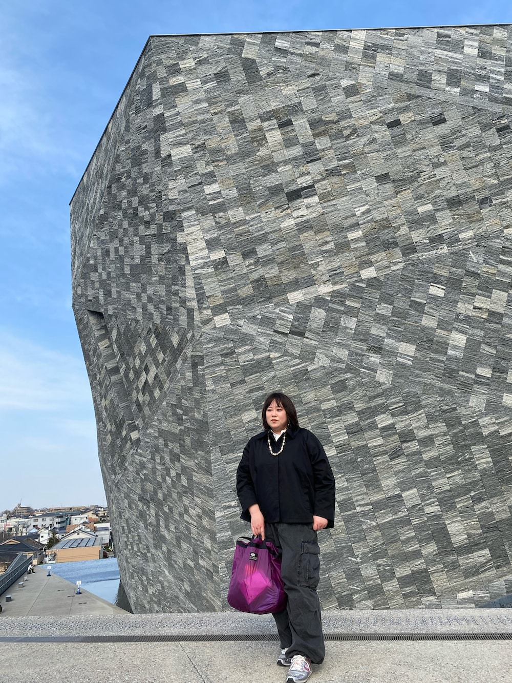 ブラック系のステンカラーコート、グレー系のデニムパンツを着用したレディースの春コーディネートの2枚目の写真