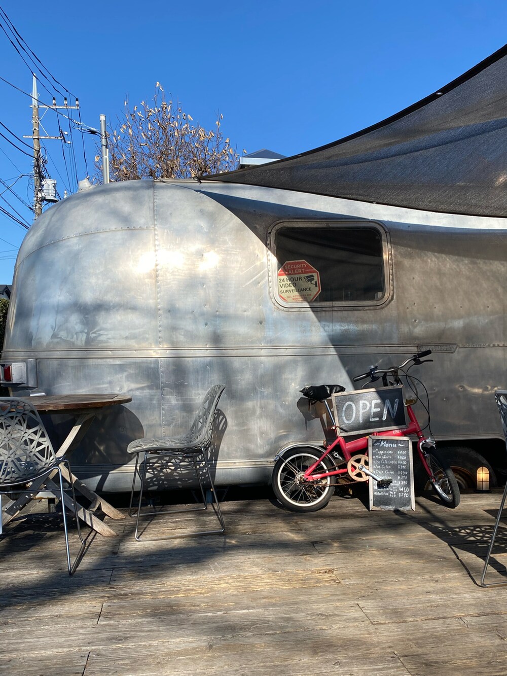 ベージュ系のステンカラーコート、ブラック系のTシャツ/カットソー、レッド系のバッグを着用したレディースの冬コーディネートの5枚目の写真