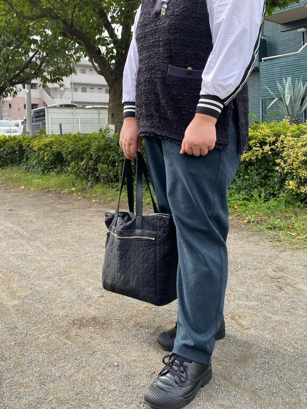 ブラック系のトートバッグ、ブラック系のベスト、ブラック系のノーカラージャケットを着用したレディースの秋コーディネートの2枚目の写真