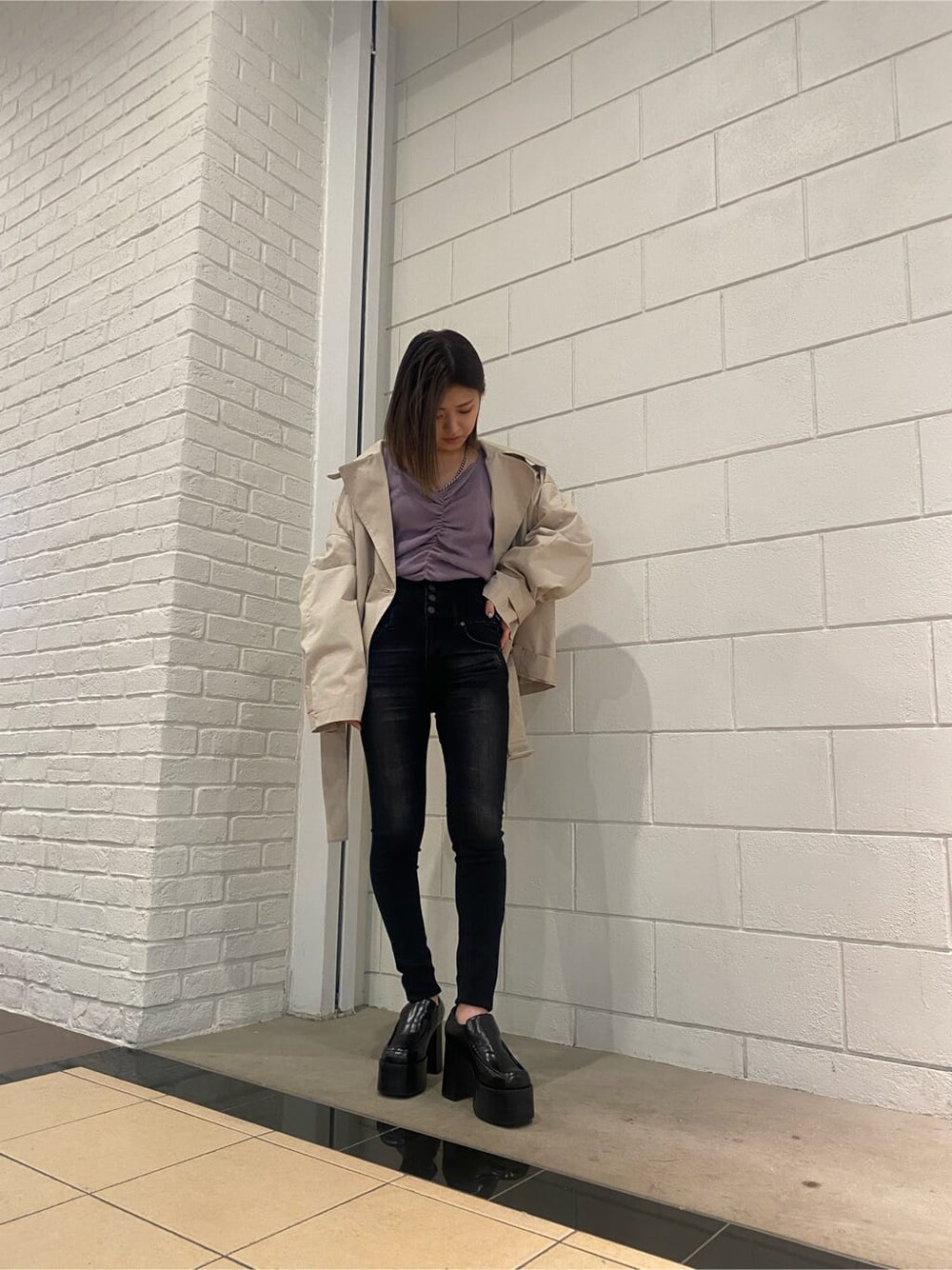 ベージュ系のトレンチコート、ブラック系のローファー、パープル系のニット/セーターを着用したレディースの冬コーディネートの2枚目の写真