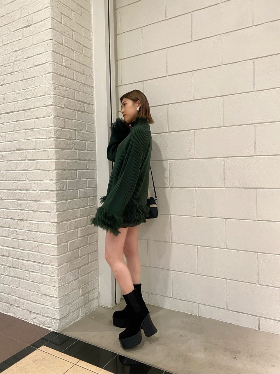 ブラック系のスカート、ブラック系のショルダーバッグ、ブラック系のブーツを着用したレディースの冬コーディネートの2枚目の写真