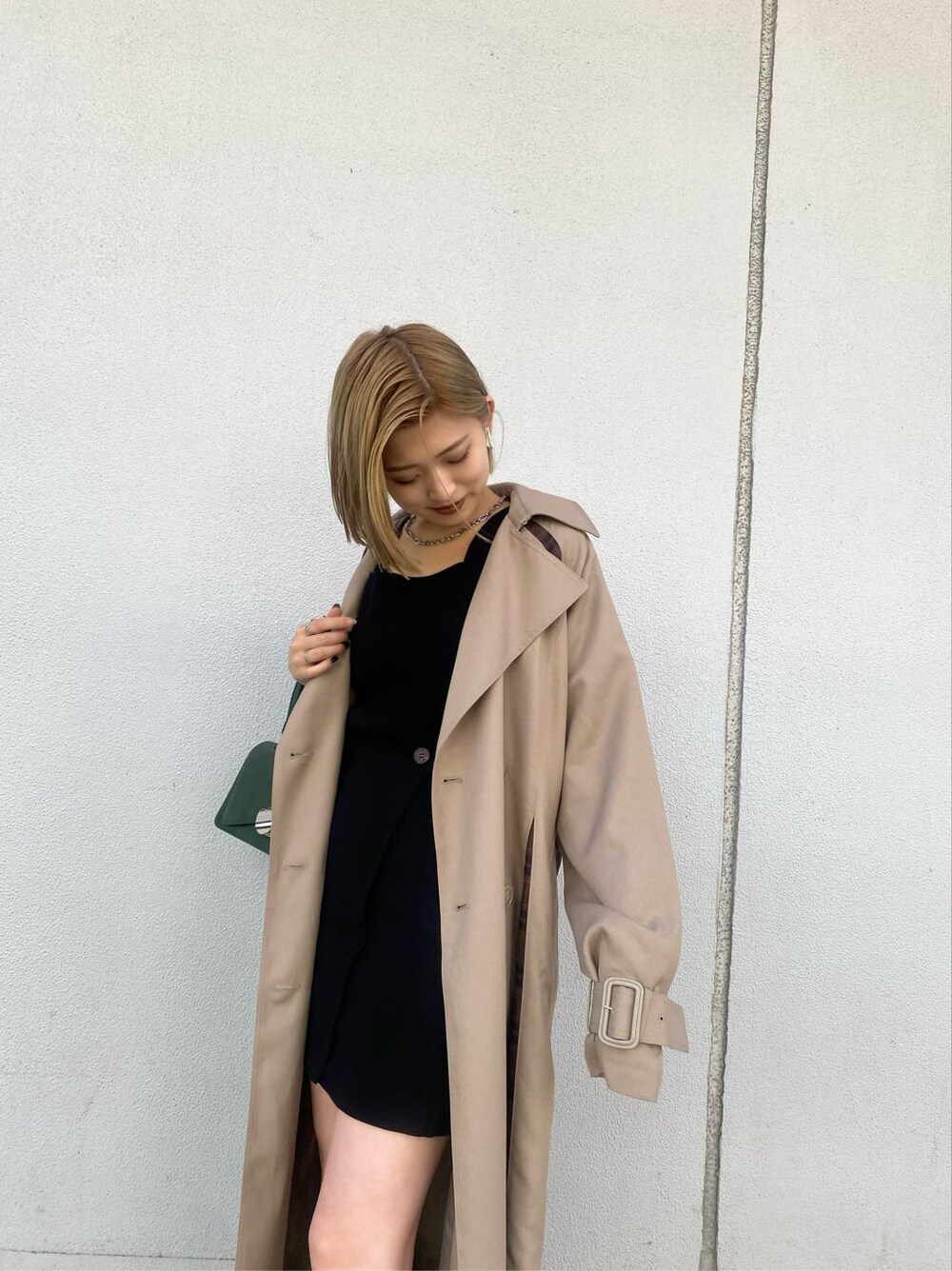 ベージュ系のトレンチコート、ブラック系のスカート、グリーン系のハンドバッグを着用したレディースの夏コーディネートの10枚目の写真