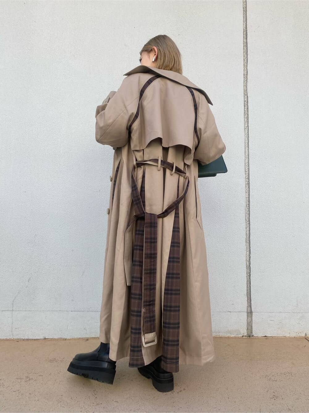 ベージュ系のトレンチコート、ブラック系のスカート、グリーン系のハンドバッグを着用したレディースの夏コーディネートの8枚目の写真