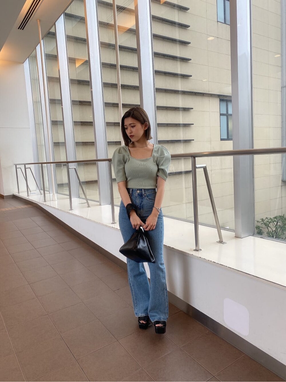 グリーン系のTシャツ/カットソー、ブラック系のハンドバッグ、ブルー系のデニムパンツを着用したレディースの夏コーディネートの2枚目の写真