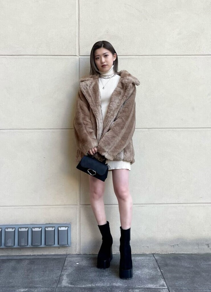 ブラック系のブーツ、ベージュ系のその他アウター、ホワイト系のワンピースを着用したレディースの冬コーディネートの2枚目の写真