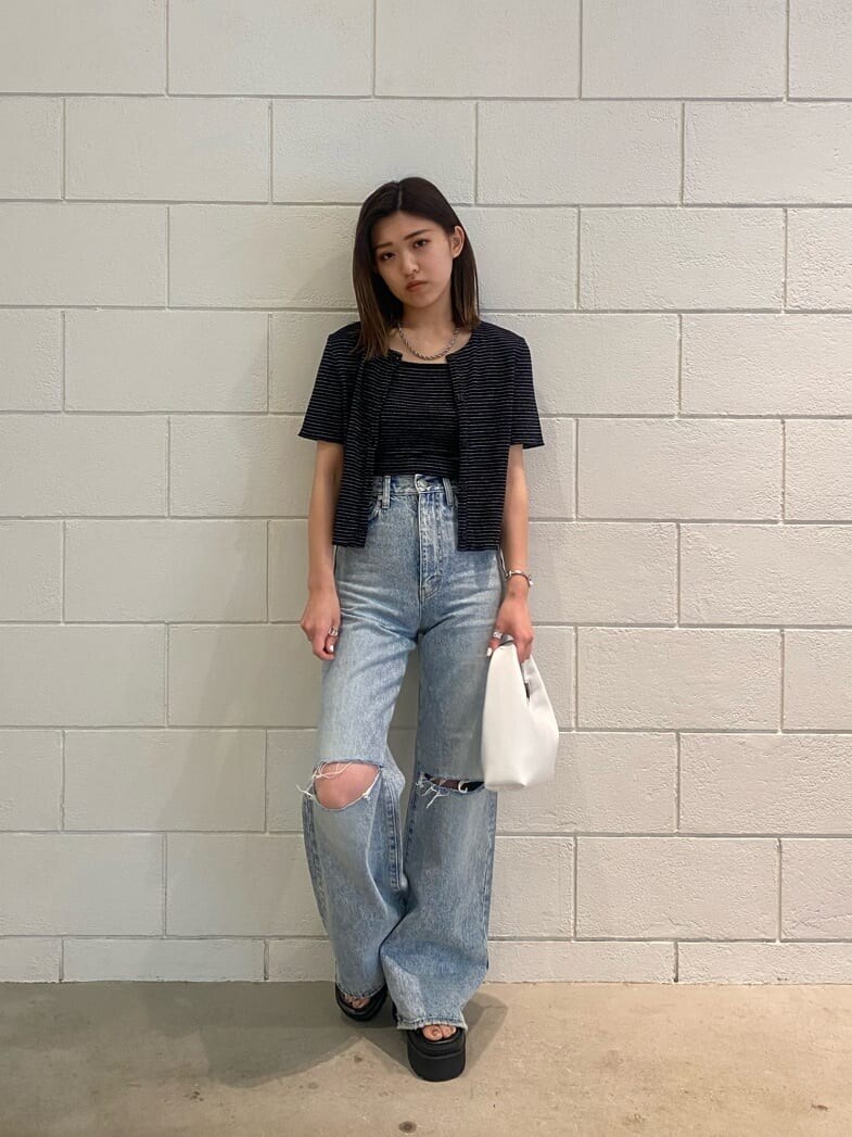 ブラック系のサンダル、ホワイト系のハンドバッグ、ブルー系のデニムパンツを着用したレディースの夏コーディネートの2枚目の写真