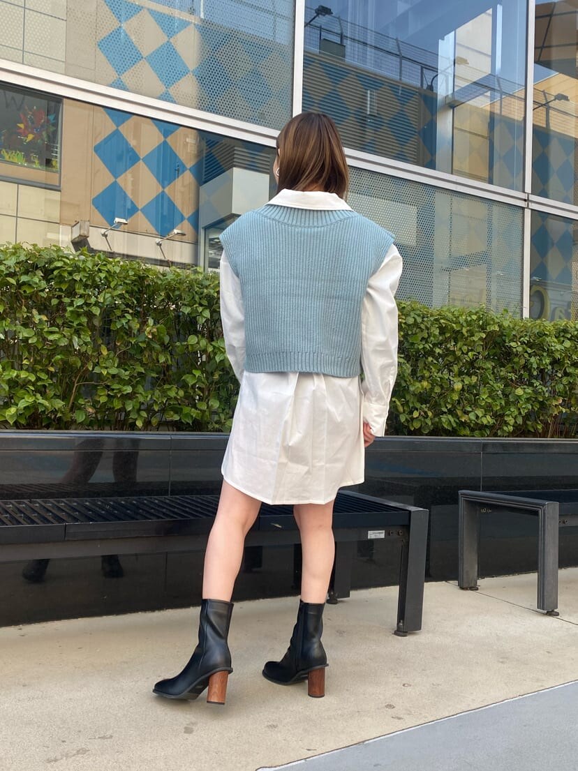 ホワイト系のシャツ/ブラウス、ブラック系のブーツ、ブルー系のベストを着用したレディースの春コーディネートの3枚目の写真