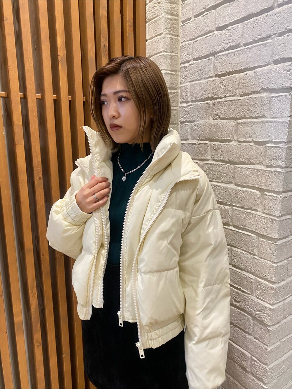 ブラック系のスカート、ホワイト系のダウンジャケット/コート、グリーン系のニット/セーターを着用したレディースの冬コーディネートの3枚目の写真