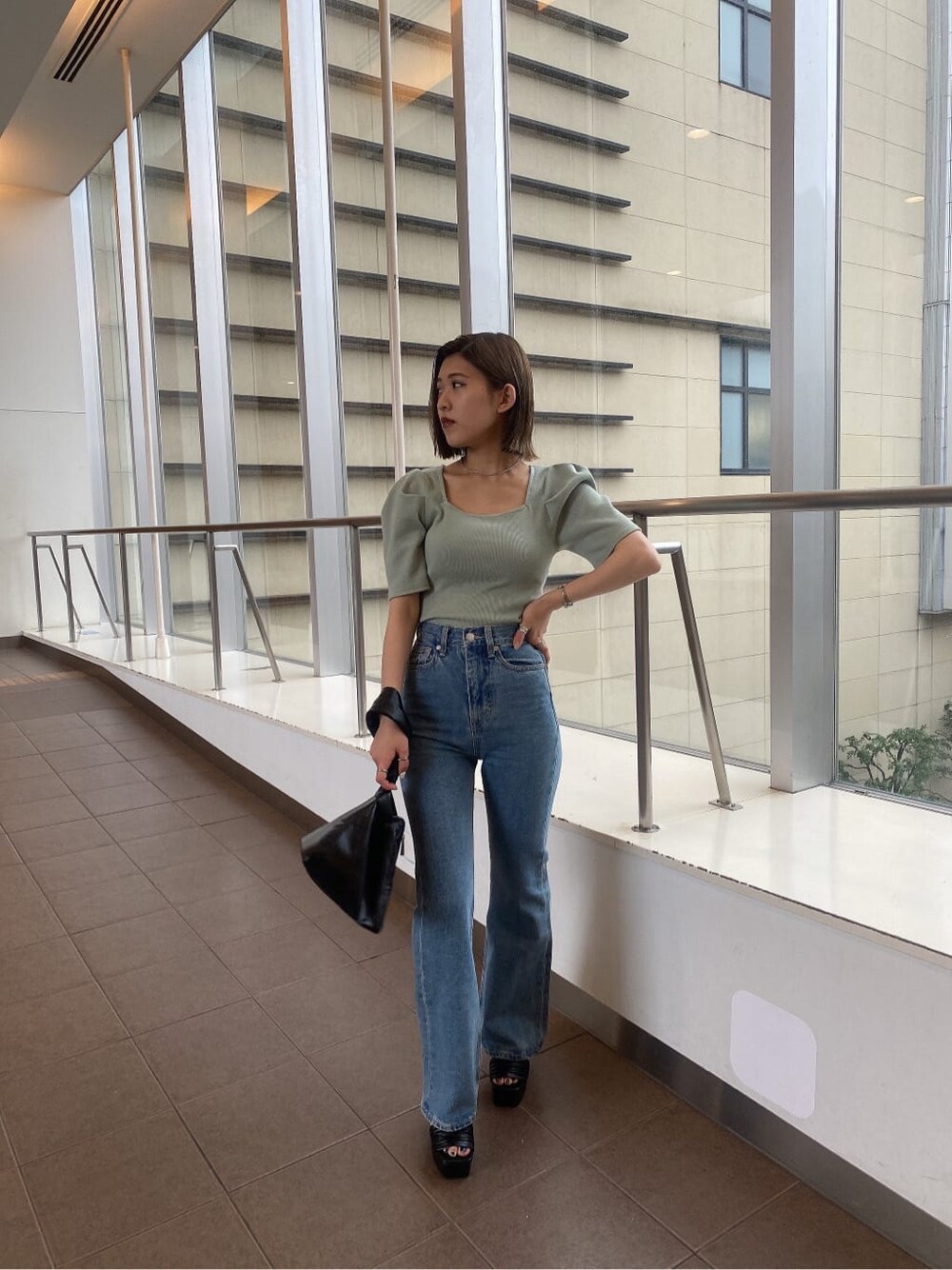 グリーン系のTシャツ/カットソー、ブラック系のハンドバッグ、ブルー系のデニムパンツを着用したレディースの夏コーディネートの3枚目の写真