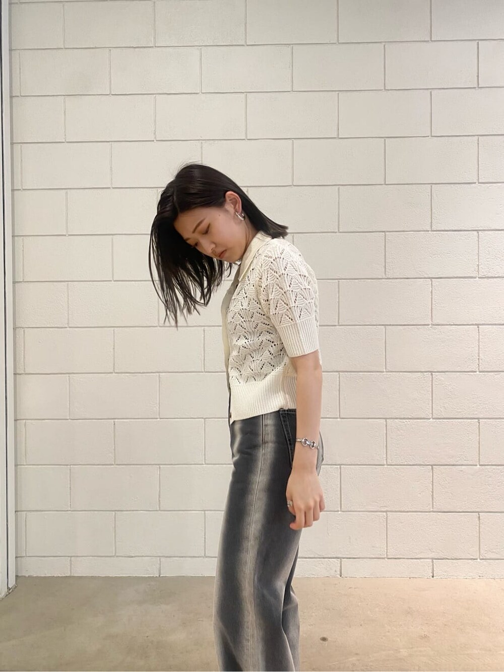 ブラック系のサンダル、ブラック系のデニムパンツ、ホワイト系のニット/セーターを着用したレディースの春コーディネートの5枚目の写真