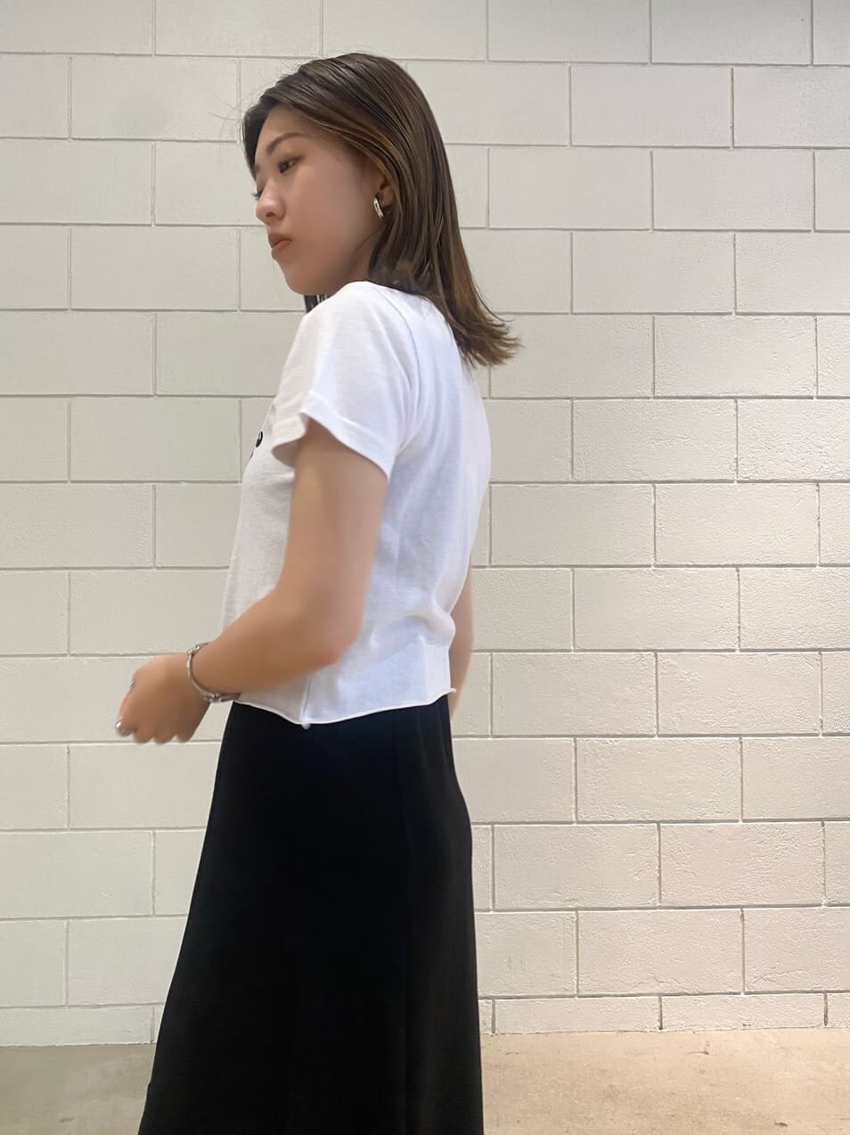 ブラック系のスカート、ブラック系のサンダル、ホワイト系のTシャツ/カットソーを着用したレディースの夏コーディネートの4枚目の写真