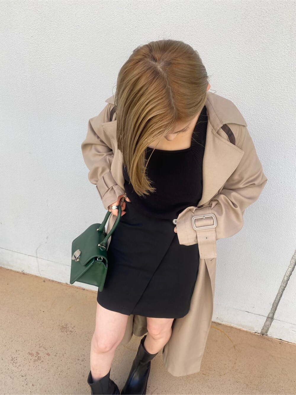 ベージュ系のトレンチコート、ブラック系のスカート、グリーン系のハンドバッグを着用したレディースの夏コーディネートの7枚目の写真